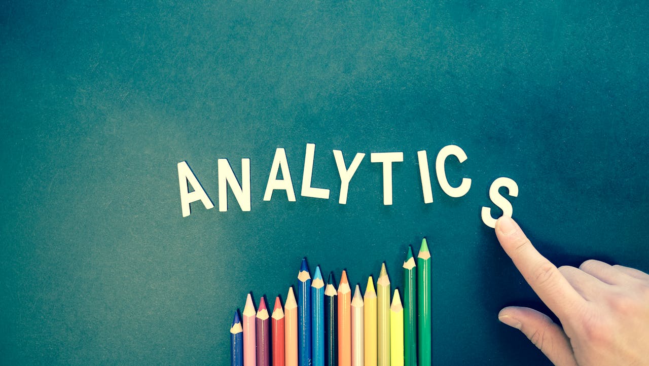 services-01 Colored pencils and letters spelling ANALYTICS on a textured background with a hand.